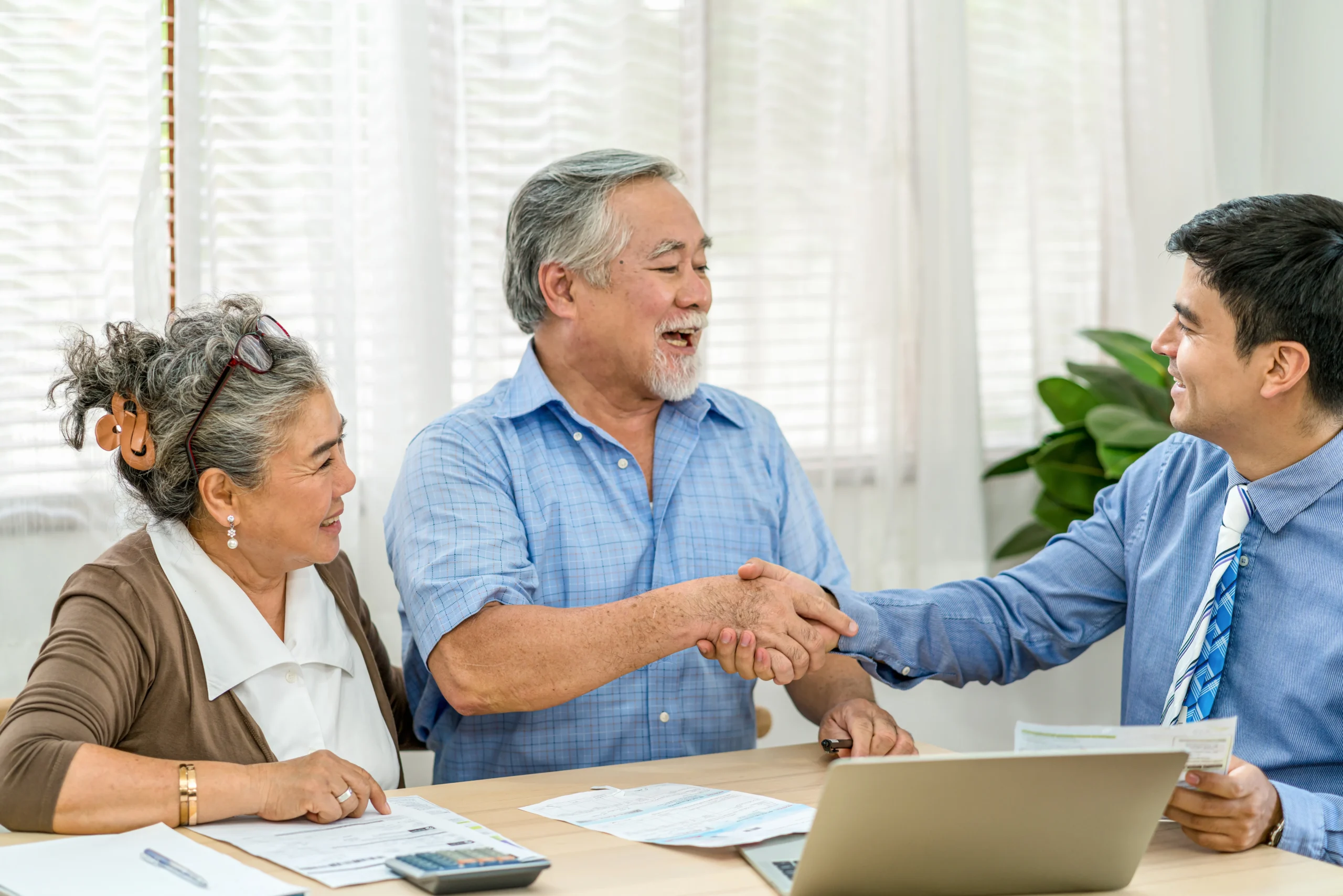Senior couple shaking hands with an insurance broker.