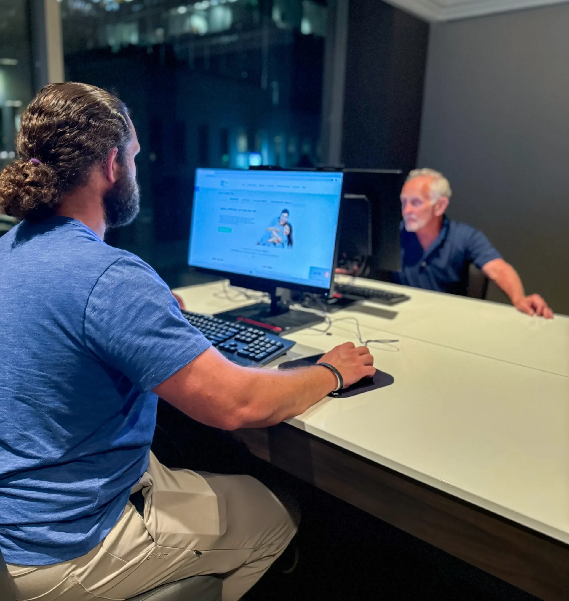 Jesse, working on Medicare plans at his computer in the foreground. Arnie is at his computer in the background.