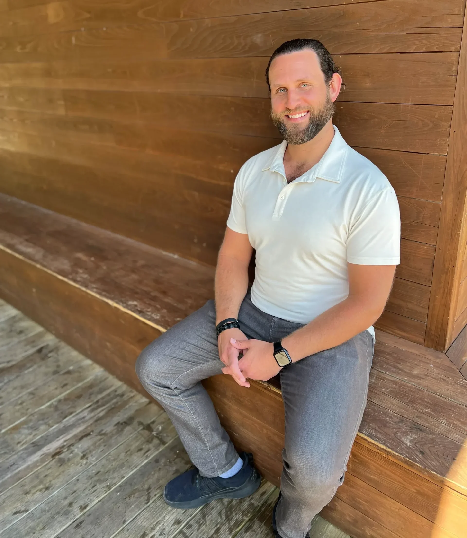 Jesse Peltz, Owner of Plan Plus for Seniors, seated on a wooden bench smiling.